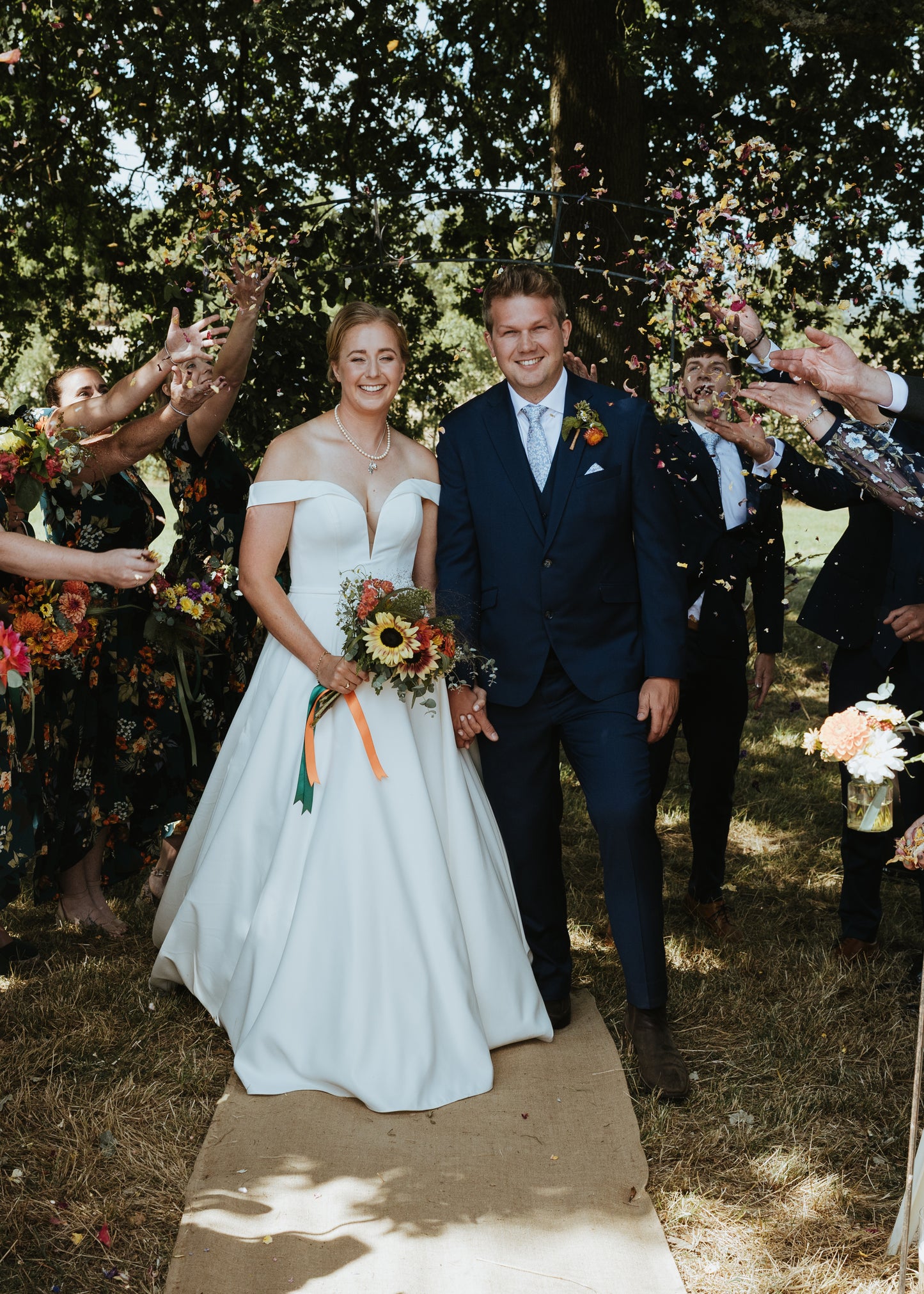 Wedding couple walking down the aisle with guests throwing confetti.
