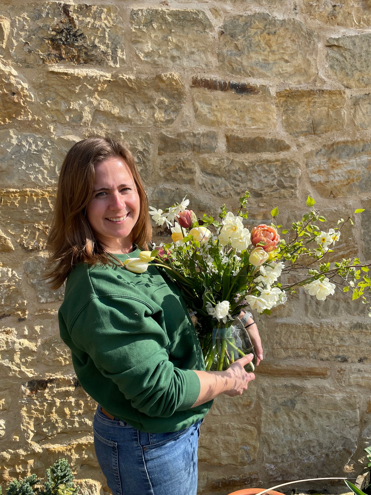 Flower farmer holding a vase of fresh picked daffodils and tulips